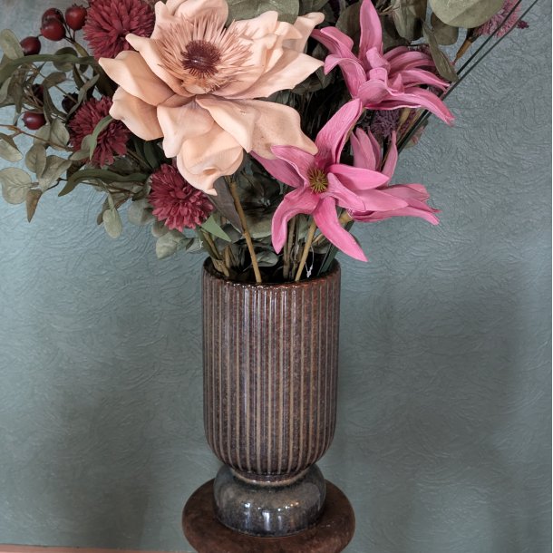 Et fokuseret billede af keramikvasens rillede m�nster, der tydeligt viser den rustikke tekstur og de m�rkebrune farvespil i materialet.