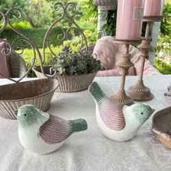 To varianter af de stribede keramikfugle i rosa og gr�nne nuancer vist sammen i et lyst milj�. Begge fugle er frostsikre og m�ler H14/L19 cm.