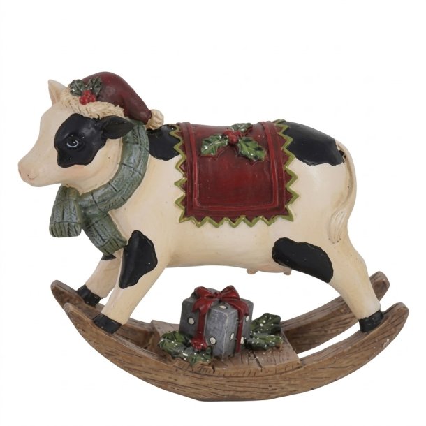 En frilagt julefigur af en sort og hvid gyngeko p� en gyngehest af tr�. Gyngekoen b�rer nissehue, gr�nt t�rkl�de og et d�kken med kristtornmotiver, og der st�r en lille gr� gave�ske ved koens f�dder p� gyngehesten.