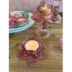 N�rbillede af rosa glasfyrfadsstager med t�ndte lys opstillet p� et tr�bord.
