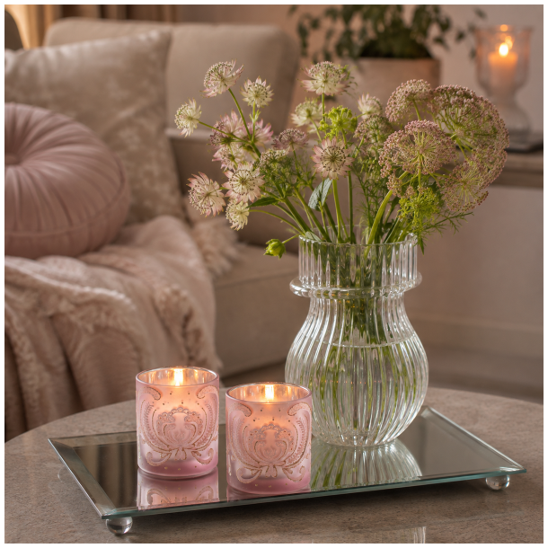 Aflangt spejlfad fra La Vida opstillet p� et bord med lyser�de glaslygter, levende lys og en ribbet glasvase med blomster.