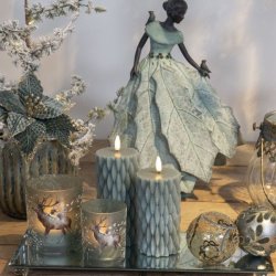 Stort spejlfad i glas pyntet med juledekorationer, bloklys med rensdyrmotiv, julekugler og en dekorativ figur.