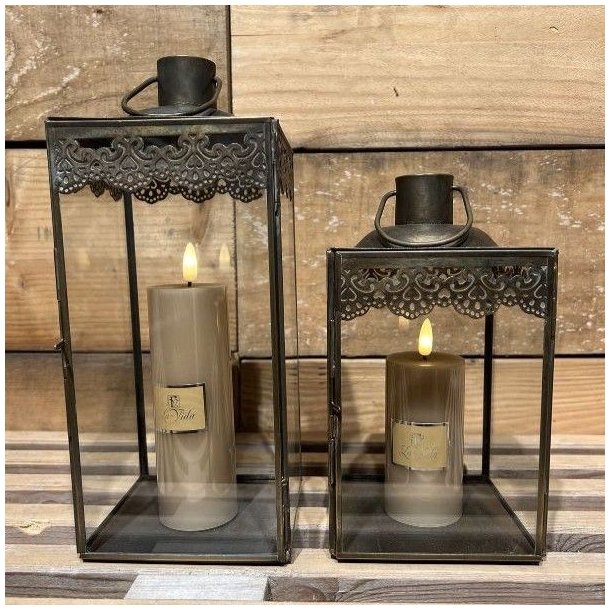 Den lille og store antikbrune lanterne opstillet indend�rs p� en tr�overflade med hyggelige, t�ndte LED-bloklys indeni.