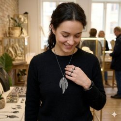 En kvinde i en sort bluse b�rer den m�rke La Vida halsk�de med det trebladede vedh�ng og en m�rkrosa sten i en smykkebutik.