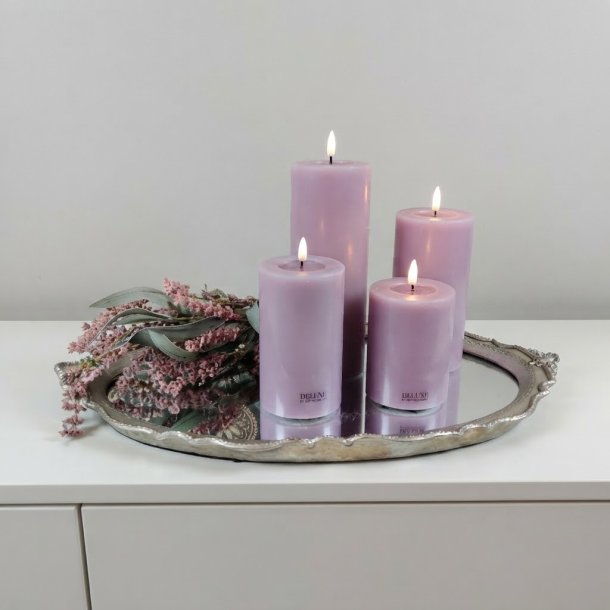 Stemningsfuldt firkantet milj�billede af de fire lilla LED-bloklys med t�ndte real flammer, placeret p� en dekorativ s�lvspejlbakke med t�rrede blomster.