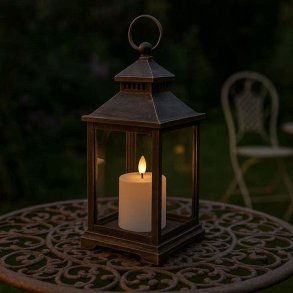 Et lille hvidt udend�rs LED-bloklys med varm flamme placeret i en hyggelig lanterne p� et havebord.