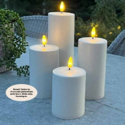 Et lille hvidt udend�rs LED-bloklys med varm flamme placeret p� et havebord.