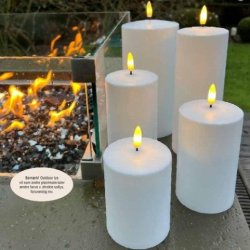 Et hvidt udend�rs LED-bloklys med en varm, t�ndt flamme placeret i en rustik lanterne p� en tr�terrasse i skumringen.