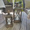 To store lanterner med hvide udend�rs LED-bloklys placeret p� en hyggelig tr�terrasse sammen med havem�bler.