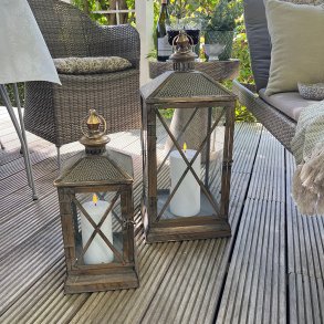 To store lanterner med hvide udend�rs LED-bloklys placeret p� en hyggelig tr�terrasse sammen med havem�bler.