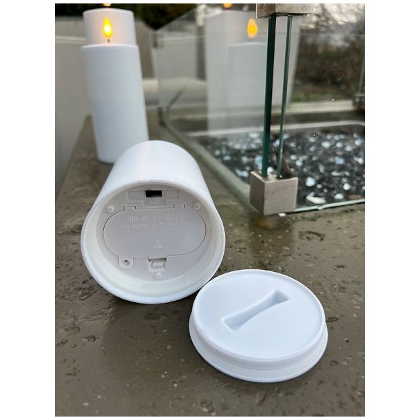 N�rbillede af bunden p� et hvidt udend�rs LED-bloklys, der viser det forseglede batterid�ksel og t�nd/sluk-knappen med timerfunktion.