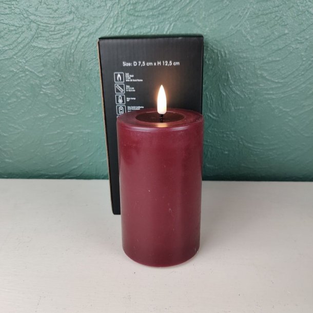Milj�billede af det t�ndte bordeauxfarvede LED-bloklys p� D 7,5 cm x H 12,5 cm st�ende foran den tilh�rende sorte produkt�ske.