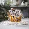 En hyggelig julescene med en fin LED-lysk�de, der lyser op omkring et fint pyntet peberkagehus placeret p� en hvid blonde-serviet.