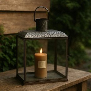 Et kvadratisk n�rbillede (image_175.png), der g�r helt t�t p� den �verste del af den antikke brune Lucca-lanterne. Billedet zoomer ind p� den slitte metalramme, den klare glasrude og den robuste jernhank, der er fastgjort med en ring. Lanternen er fritlagt og fremst�r med en tydelig, ru og rustik tekstur, der inviterer til at r�re ved metallet.