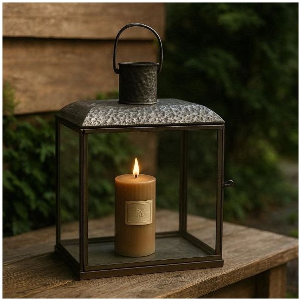 Et kvadratisk n�rbillede (image_175.png), der g�r helt t�t p� den �verste del af den antikke brune Lucca-lanterne. Billedet zoomer ind p� den slitte metalramme, den klare glasrude og den robuste jernhank, der er fastgjort med en ring. Lanternen er fritlagt og fremst�r med en tydelig, ru og rustik tekstur, der inviterer til at r�re ved metallet.