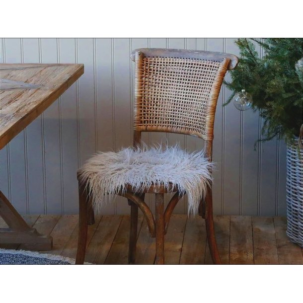 En klassisk tr�stol med flettet rygl�n, hvor et lysegr�t imiteret lammeskind er lagt som en bl�d og langh�ret s�dehynde.