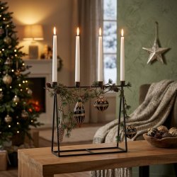 Stemningsfuldt firkantet milj�billede af den antikke sorte lysestage med fire t�ndte hvide kronelys, pyntet med grangrene og m�rke julekugler p� et tr�bord.