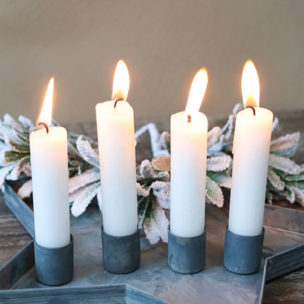 Stemningsfuldt milj�billede af fire t�ndte hvide kronelys placeret i de magnetiske zinklysholdere p� en stjerneformet metalbakke med grangrene i baggrunden.