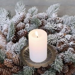 Antik messing lysholder med spyd monteret med et t�ndt hvidt bloklys i en sned�kket krans af grangrene og kogler.