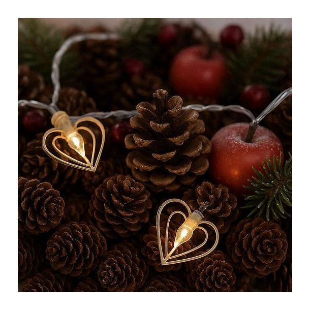 To t�ndte kobberfarvede hjerte-lyskilder fra en lysk�de, smukt placeret midt i en rustik juledekoration af brune grankogler og r�de �bler.