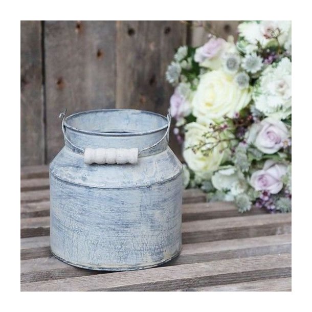 Den rustikke m�lkekande i zink st�r p� en r� tr�b�nk foran en rustik tr�v�g. Ved siden af kanden ses en smuk buket med roser og t�rrede blomster.