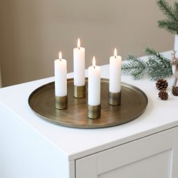 Firkantet billede af et komplet adventss�t p� en hvid sk�nk. De fire magnetiske lysholdere i antique messing, t�ndt med hvide kronelys, er placeret i en samlet gruppe i midten af den store, runde metalbakke. Bakken st�r p� en ren, hvid overflade mod en lys baggrund.