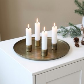 Firkantet billede af et komplet adventss�t p� en hvid sk�nk. De fire magnetiske lysholdere i antique messing, t�ndt med hvide kronelys, er placeret i en samlet gruppe i midten af den store, runde metalbakke. Bakken st�r p� en ren, hvid overflade mod en lys baggrund.