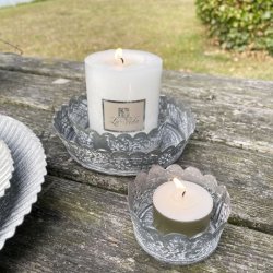 Antik gr� metalfade i to st�rrelser med t�ndt hvidt bloklys og fyrfadslys placeret p� et rustikt tr�bord.