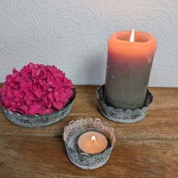 Tre antik gr� metalfade p� et tr�bord indrettet med en pink hortensia, et t�ndt bloklys og et lille fyrfadslys.