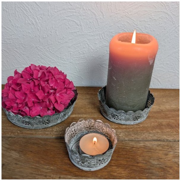 Tre antik gr� metalfade p� et tr�bord indrettet med en pink hortensia, et t�ndt bloklys og et lille fyrfadslys.