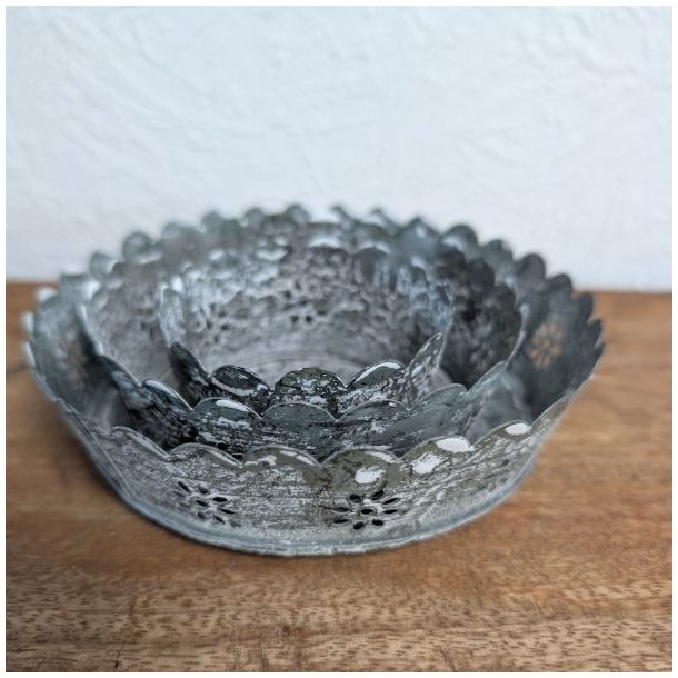 Tre antik gr� metalfade i forskellig st�rrelse samlet inde i hinanden p� et tr�bord, s� det fine m�nster og den patinerede finish ses tydeligt.