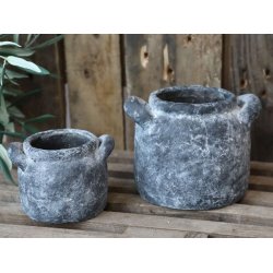 To franske havekrukker i cement med antik kul patina opstillet p� en rustik tr�overflade. Krukkerne har h�ndtag og et r�t, patineret look.