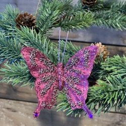 Fuchsiafarvet organza sommerfugl med glimmer sat p� en grangren med sm� kogler.