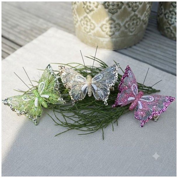 Tre dekorationssommerfugle i organza (gr�n, champagne og rosa) med glimmer og hvide aftegninger samlet p� en gr�n gren.