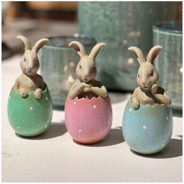 Lille p�skehare i lyser�d �ggeskal placeret dekorativt sammen med for�rsblomster og p�skepynt