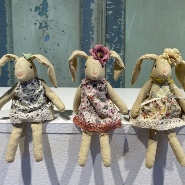 Tre siddende p�skeharer i vintagestil med m�nstrede bomuldskjoler i en lys opstilling.
