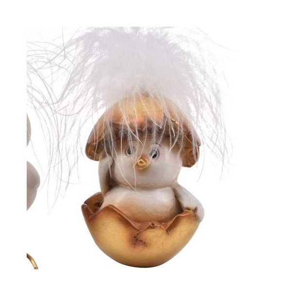 Fritlagt figur af en hvid p�skekylling med bl�de fjer, der sidder nede i en guld�ggeskal.