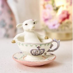 Dekorativt p�skelam i en kop placeret i en lys for�rsopstilling med blomster i baggrunden.