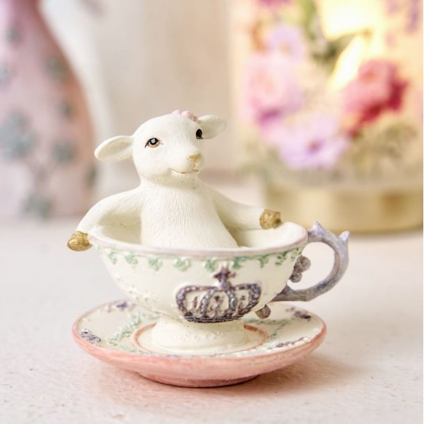 Dekorativt p�skelam i en kop placeret i en lys for�rsopstilling med blomster i baggrunden.