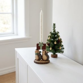 Julelysestage formet som to pindsvin med gave og et hvidt kalenderlys med guld-tal, placeret p� en hvid sk�nk ved siden af et lille kunstigt juletr�.