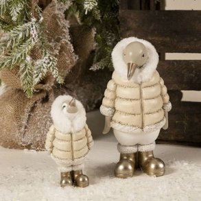 Et stemningsfuldt milj�billede, der viser de to tilg�ngelige varianter af de detaljerede pingvin-figurer. Den store (H20,5 cm) og lille (H13,5 cm) pingvin st�r i kunstig sne. De s�lges enkeltvis og assorteret. De b�rer beige dunjakker og skinnende guldst�vler.