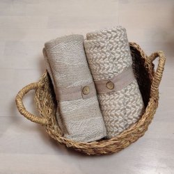 Milj�billede af en bl�d beige plaid lagt dekorativt i en flettet kurv.