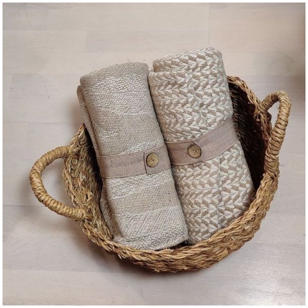 Milj�billede af en bl�d beige plaid lagt dekorativt i en flettet kurv.