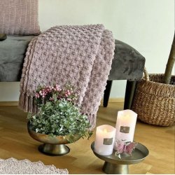 Milj�billede af den rosa plaid draperet over en stilfuld stol, hvilket viser m�nsterets spil og farvens varme i et naturligt lys.