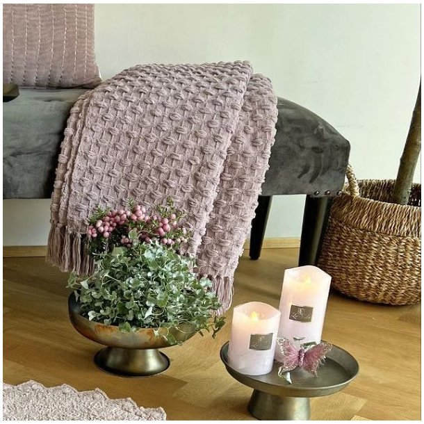 Milj�billede af den rosa plaid draperet over en stilfuld stol, hvilket viser m�nsterets spil og farvens varme i et naturligt lys.