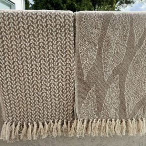 De to beige bomuldsplaider med frynser vist sammen, s� man kan se de to forskellige m�nstre.