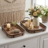 Firkantet milj�billede af to rektangul�re dekorationsbakker i m�rkt tr� med jernkant og h�ndtag p� en hvid sk�nk. Den store bakke er pyntet med en hvid vase med friske blomster samt tre hvide bloklys, mens den lille bakke har et lyst stearinlys og sm� pyntegenstande.