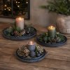 Runde sorte metalfade opstillet som hel�rsdekorationer med bloklys, gran og kogler p� et tr�bord.