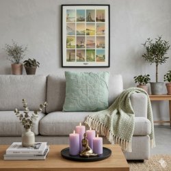 rundt-fad-i-trae-la-vida-sort-miljoe-sofabord-stue Det runde sorte tr�fad fra La Vida ligger p� et lyst tr�sofabord i en stue foran en gr� sofa og er pyntet med fire t�ndte lilla bloklys og en lille gylden ballerinafigur.