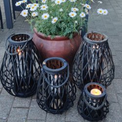 lanterner i sort flet med lys i st�r p� terrassen ved en blomsterkrukker med magurieter